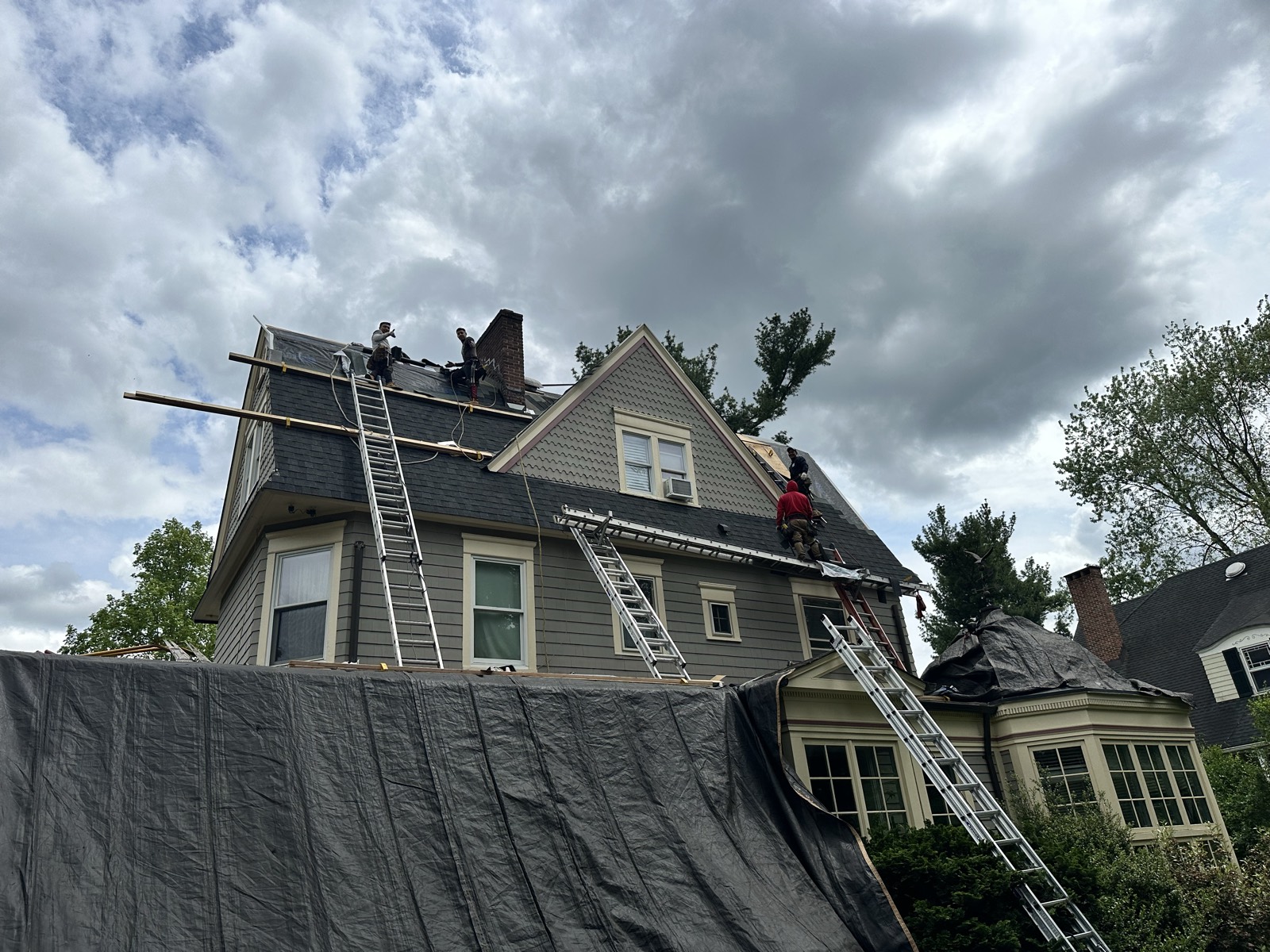 Roofing crew on ridge multi story Victorian three ladders NJ